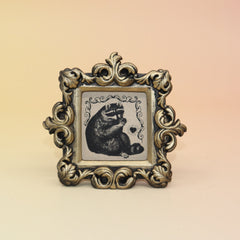 The Raccoon Mini Vintage Framed Print on a pink and yellow background.