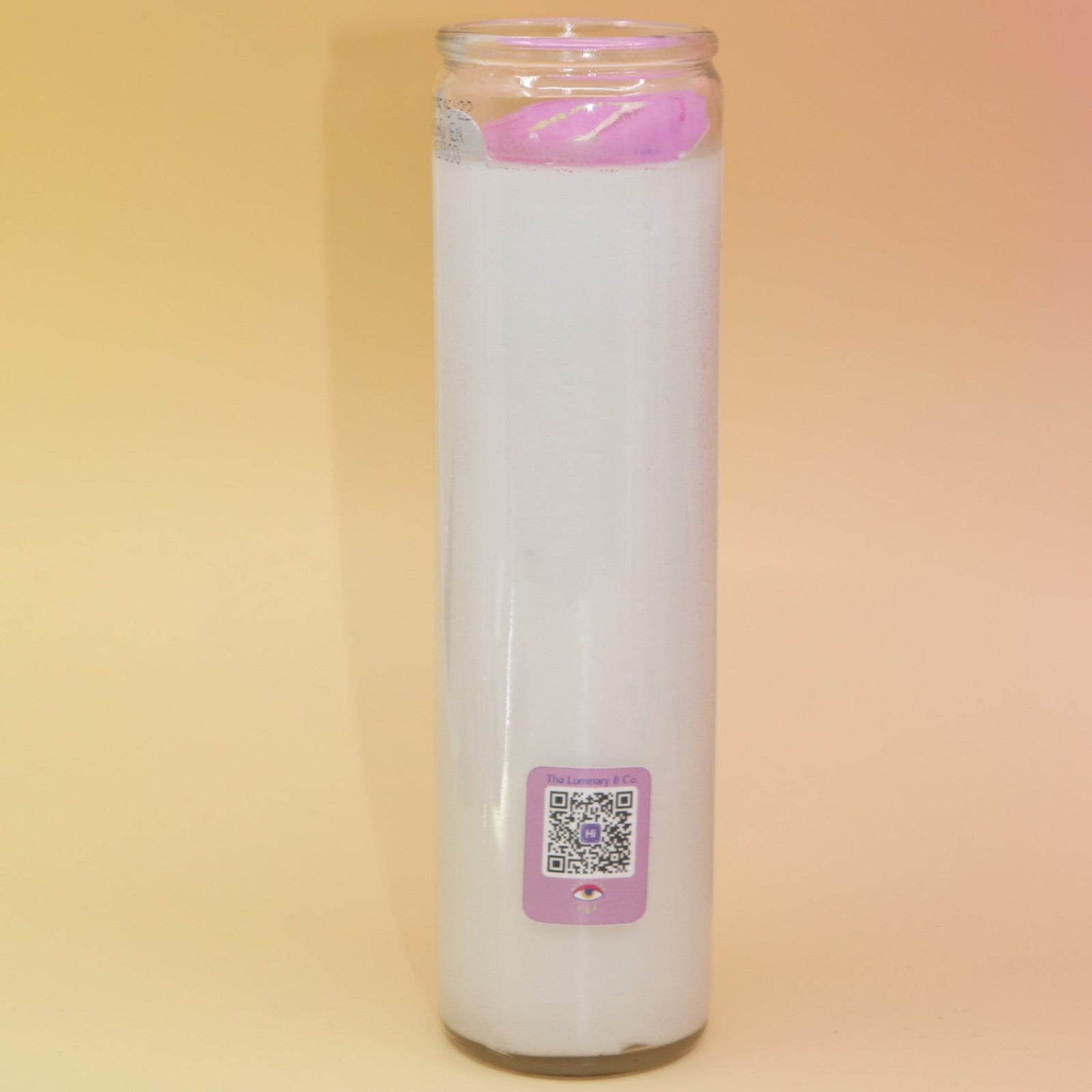 The back of the The Luminary Co Altar Candle on a pink and yellow background.