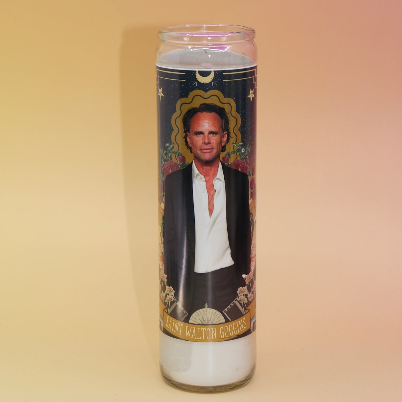 The Walton Goggins Devotional Prayer Candle on a pink and yellow background