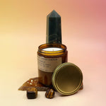 The Spiced Pumpkin Standard 7.2 oz Soy-Wax Candle on an agate slice and in front of a crystal tower all on a pink and yellow background.