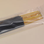 An up-close image of the P.F. Candle Co. incense sticks on a pink and yellow background.
