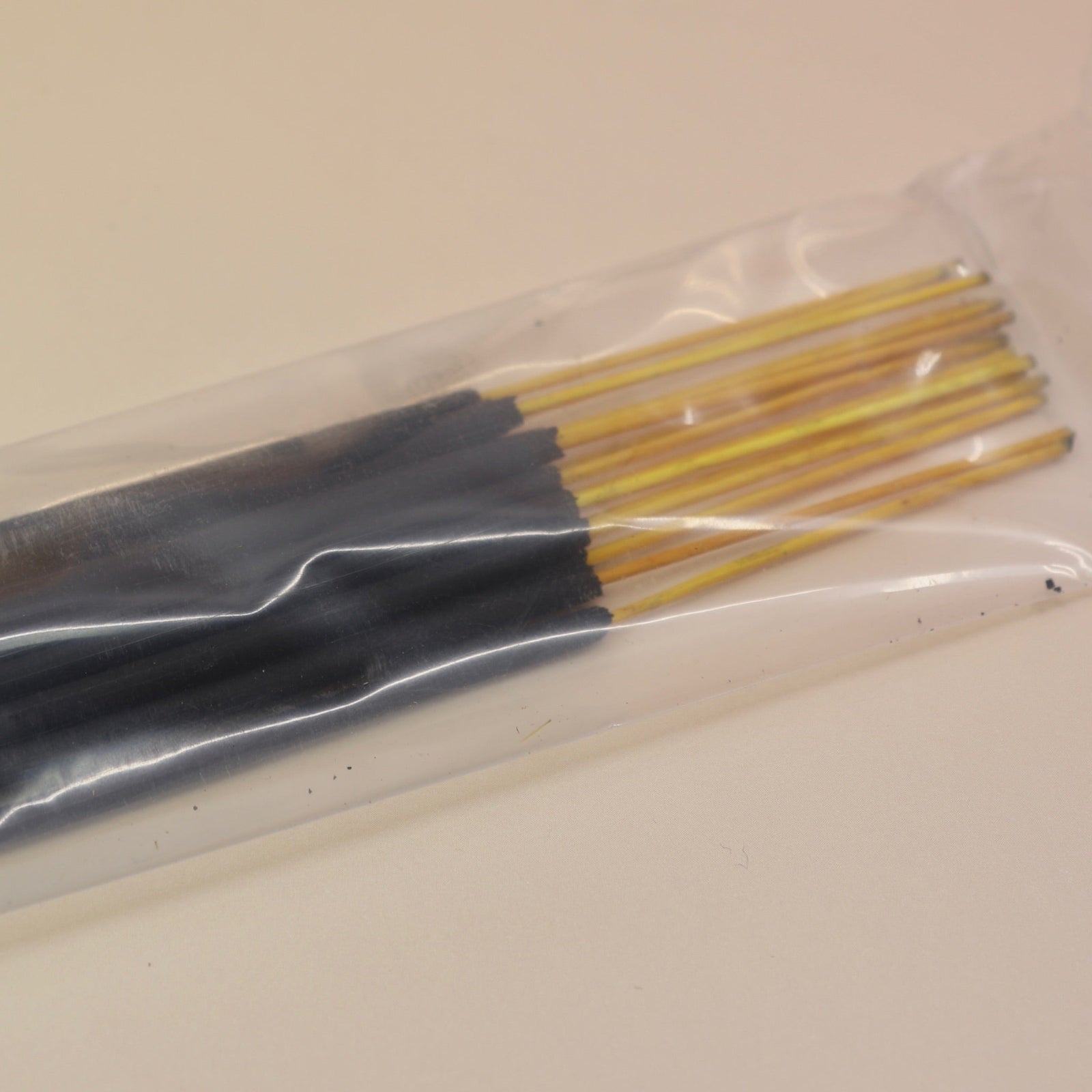 An up-close image of the P.F. Candle Co. incense sticks on a pink and yellow background.