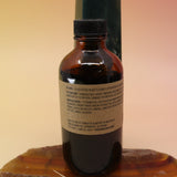 The P.F. Candle Co. Spruce - 3.5 oz Reed Diffuser on an agate slice in front of a crystal tower, showing off the back.