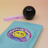A small - medium Mystery Crystal Sphere Bag open with its contents on a pink and yellow background.