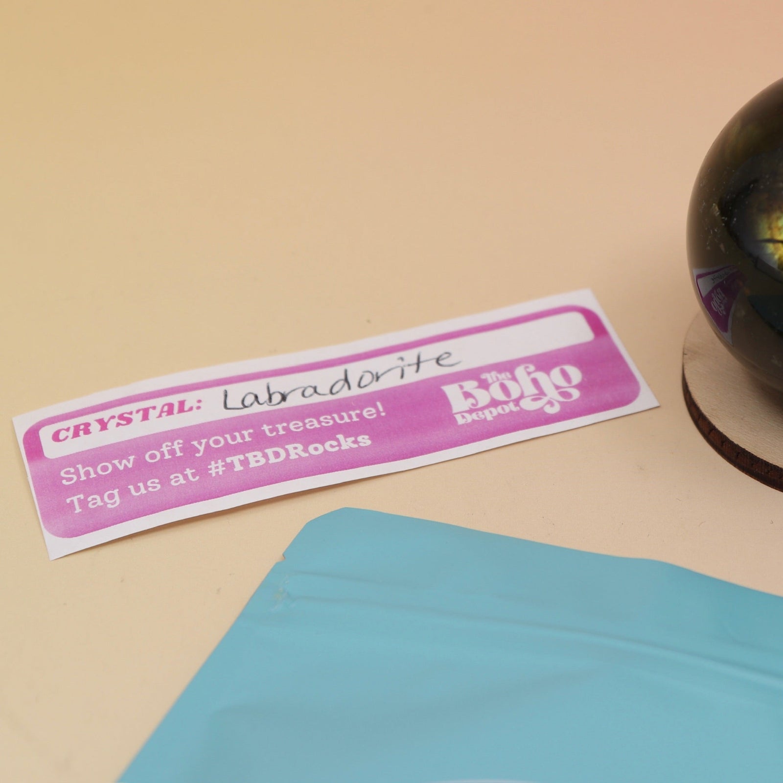 An up-close image of a small - medium Mystery Crystal Sphere Bag open with its contents on a pink and yellow background.