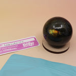 An up-close image of a small - medium Mystery Crystal Sphere Bag open with its contents on a pink and yellow background.