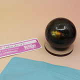 An up-close image of a small - medium Mystery Crystal Sphere Bag open with its contents on a pink and yellow background.
