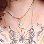 An up-close image of a woman wearing the Opalite Crescent Necklace – Gold Chain Crystal Moon Pendant.