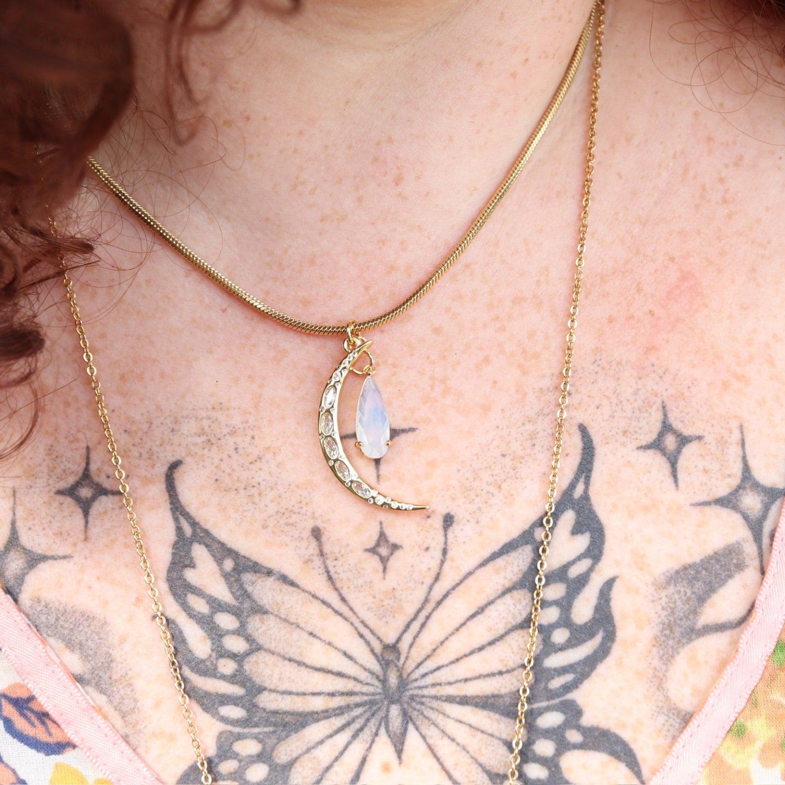 An up-close image of a woman wearing the Opalite Crescent Necklace – Gold Chain Crystal Moon Pendant.