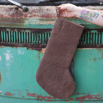 Someone holding the Handmade Gray Mushroom Felt Boho Stocking in front of a vintage teal Volkswagen bus, showing off the back.