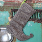 The Handmade Green Mushroom Wool Felt Boho Stocking hanging in front of a teal vintage Volkswagen bus, showing off the back.