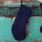 Someone holding the Mystical Moon Phase Felt Holiday Pure Wool Handcrafted Stocking in front of a vintage teal Volkswagen bus, showing off the back.