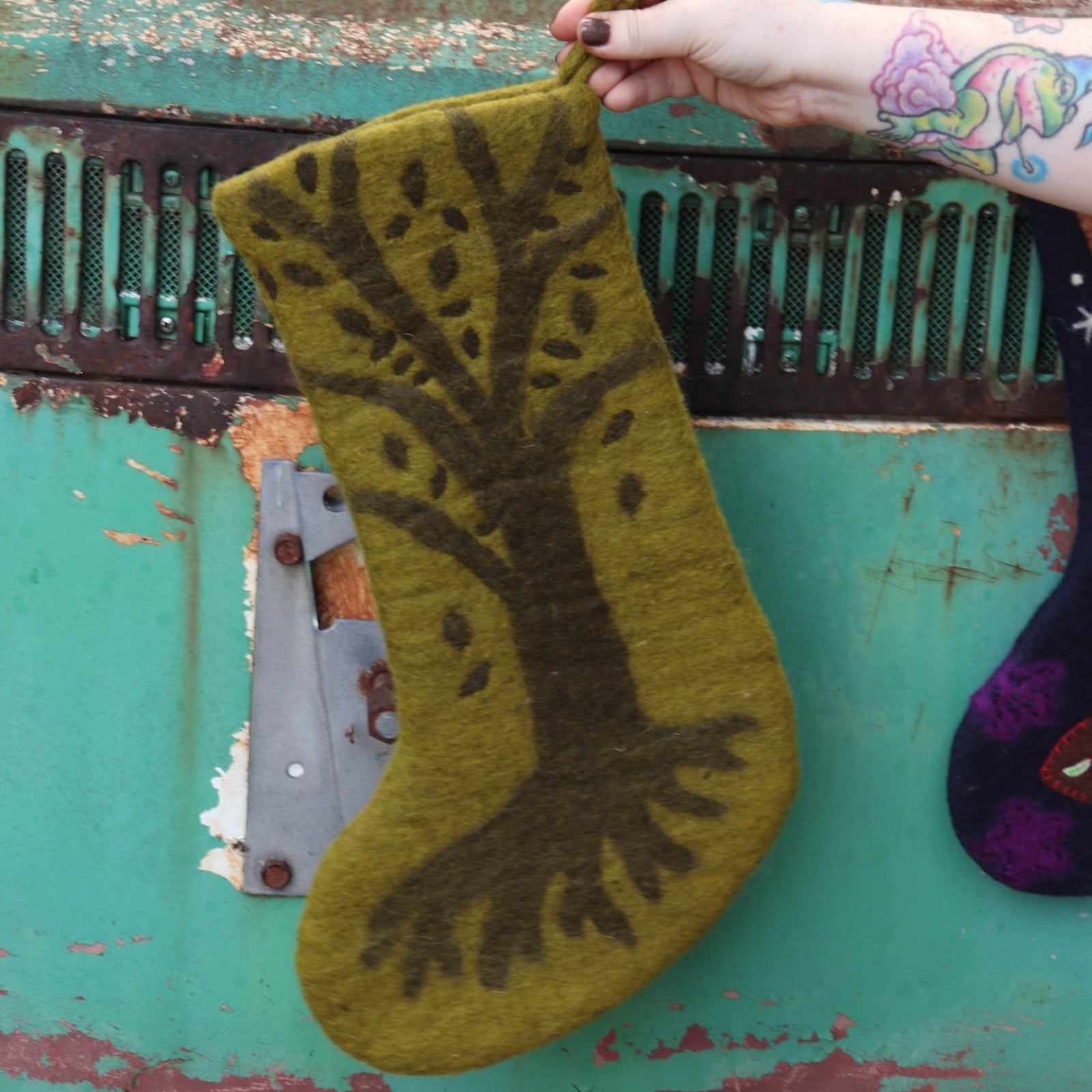 Someone holding the Tree of Life Mystical Felt Stocking in front of a vintage teal Volkswagen bus.