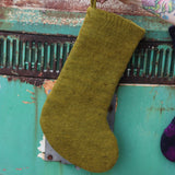 Someone holding the Tree of Life Mystical Felt Stocking in front of a vintage teal Volkswagen bus, showing off the back.