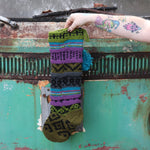 Someone holding up the Wool Handcrafted Diamond Stocking in front of a vintage teal Volkswagen bus, showing off the back.