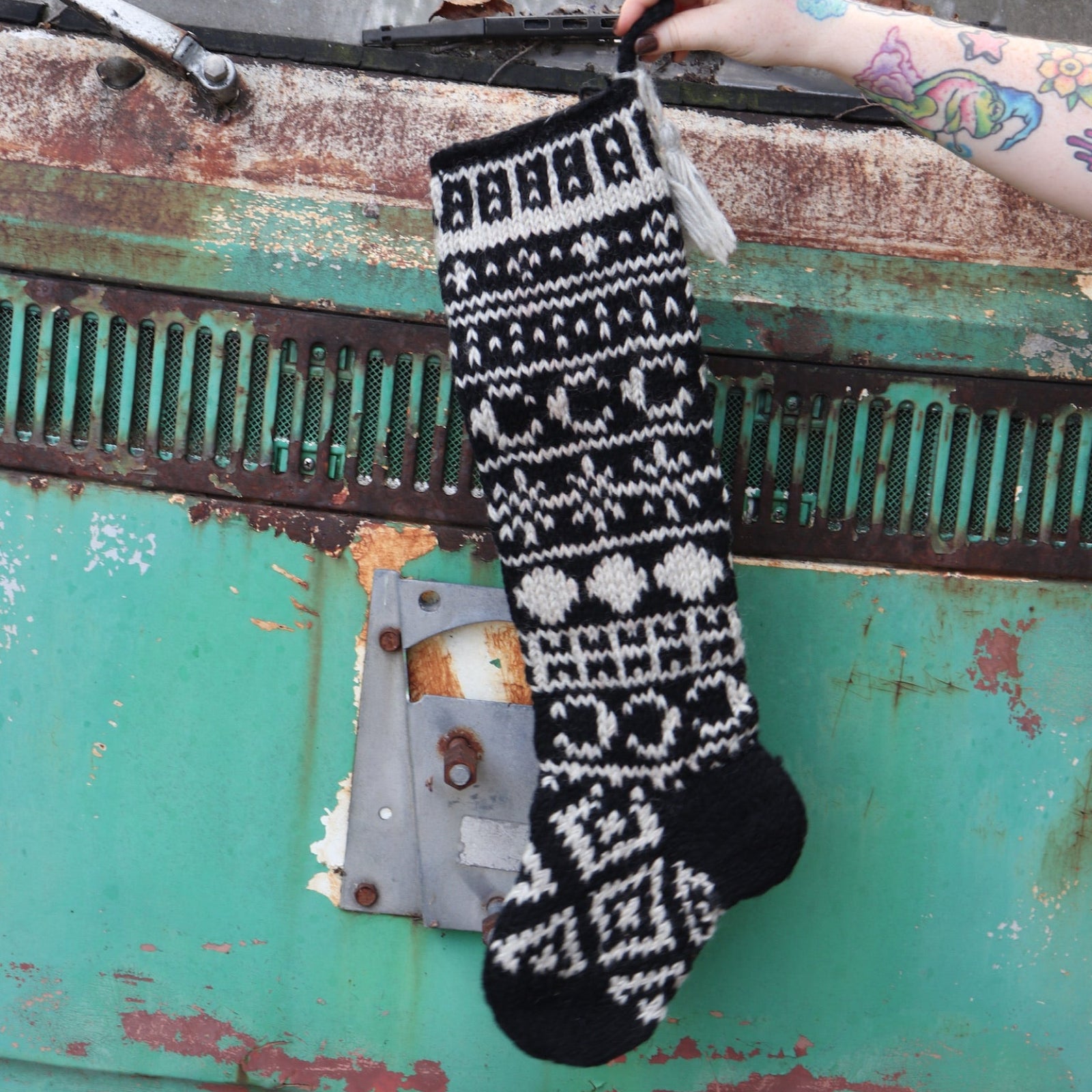 Someone holding the Celestial Hand Knit Stocking in front of a vintage teal Volkswagen bus.