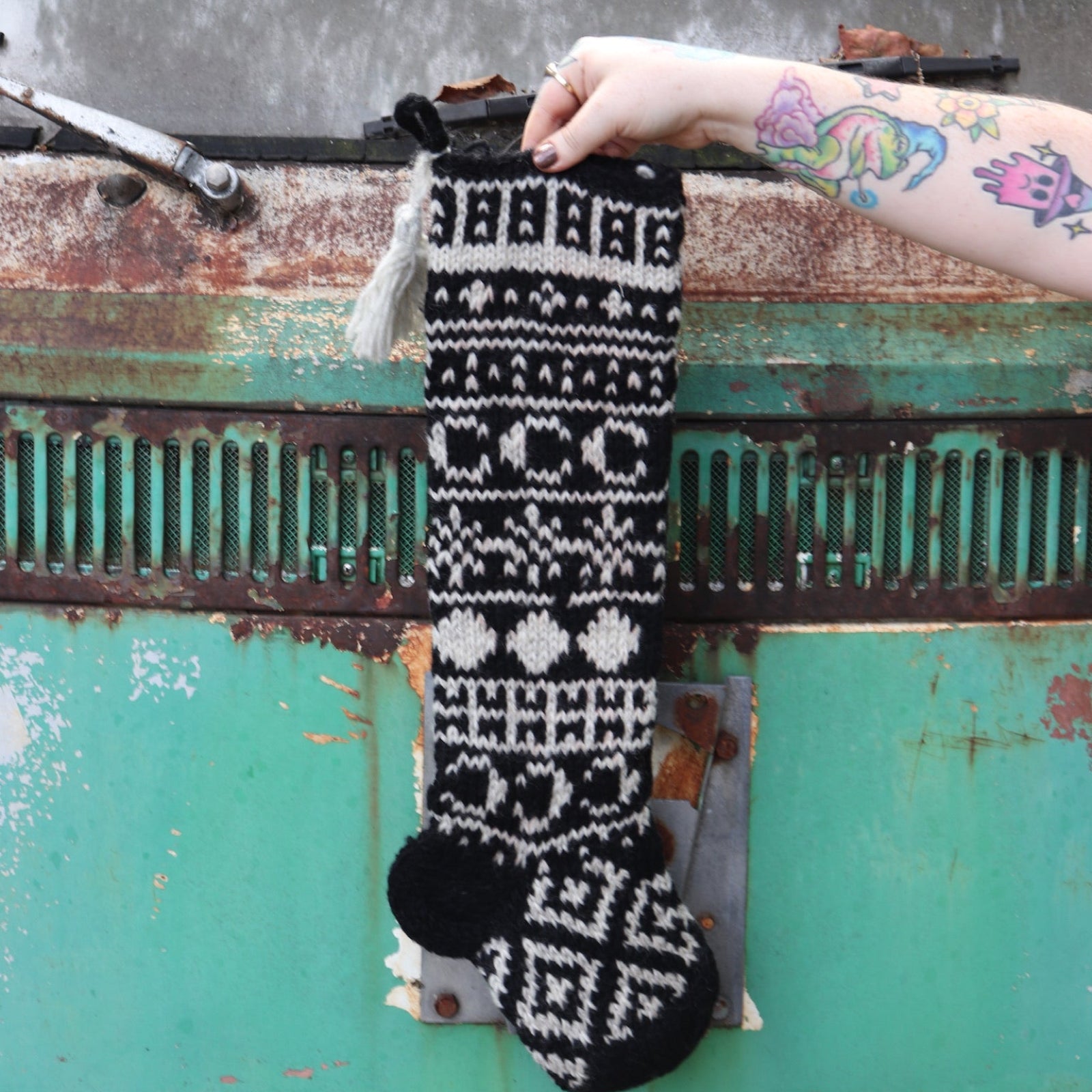 Someone holding the Celestial Hand Knit Stocking in front of a vintage teal Volkswagen bus.