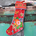 Someone holding one of the Red Floral Embroidered Stockings in front of a vintage teal Volkswagen bus.