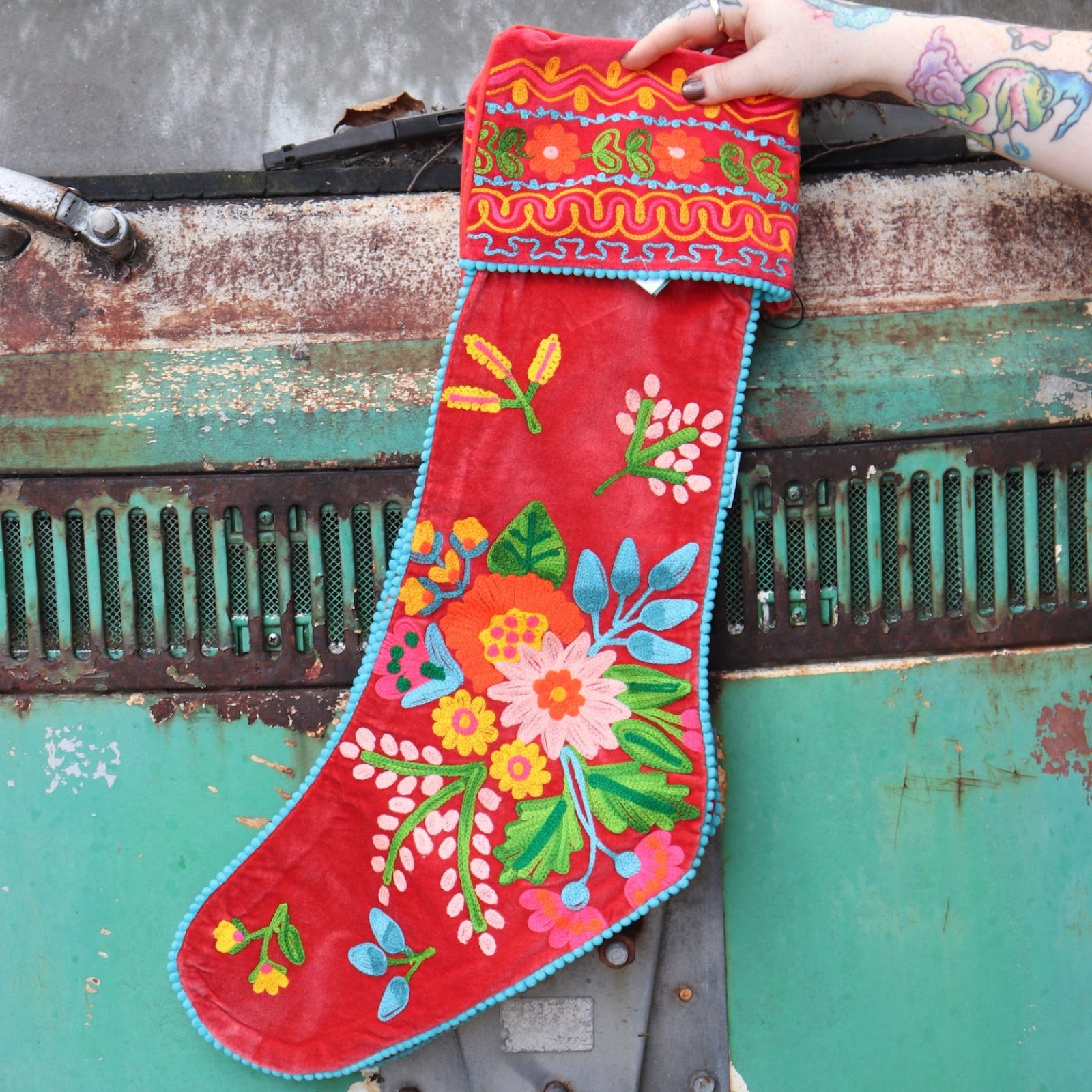 Someone holding one of the Red Floral Embroidered Stockings in front of a vintage teal Volkswagen bus.