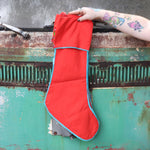 Someone holding one of the Red Floral Embroidered Stockings in front of a vintage teal Volkswagen bus, showing off the back.