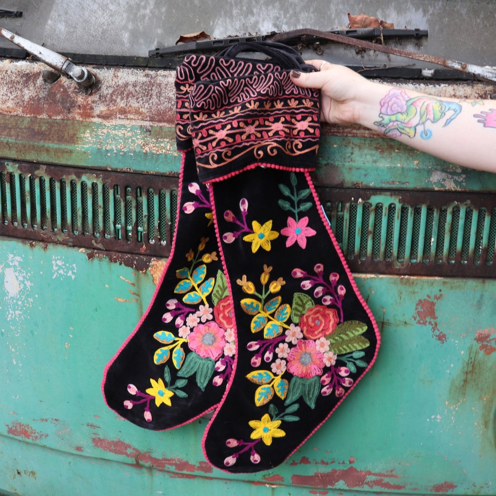 Someone holding the Set of 2 Black Floral Embroidered Stockings in front of a vintage teal Volkswagen bus.