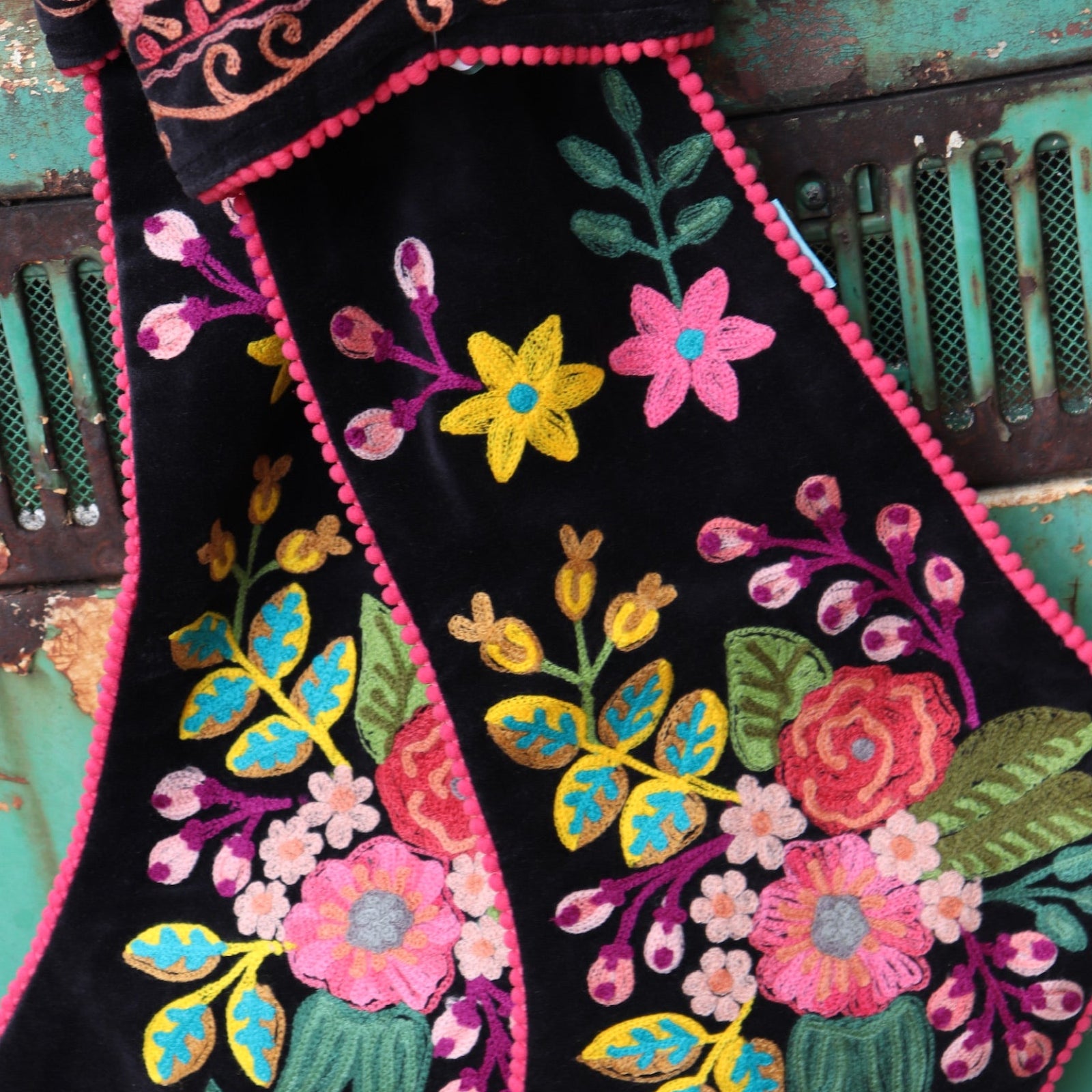 An up-close image of t the Set of 2 Black Floral Embroidered Stockings in front of a vintage teal Volkswagen bus.