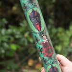 Someone holding the Krampus Children Collage Matte Fine Wrapping Paper in front of greenery.
