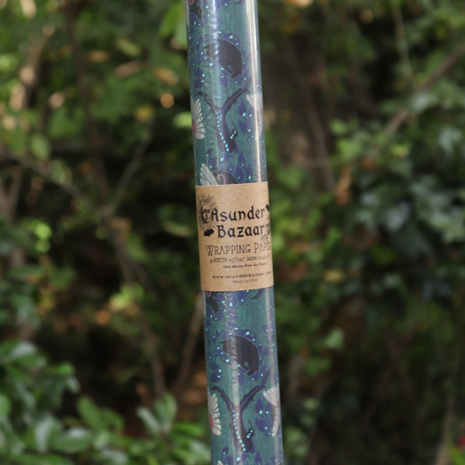The Nouveau Twilight Butterflies Matte Fine Wrapping Paper in front of some greenery.