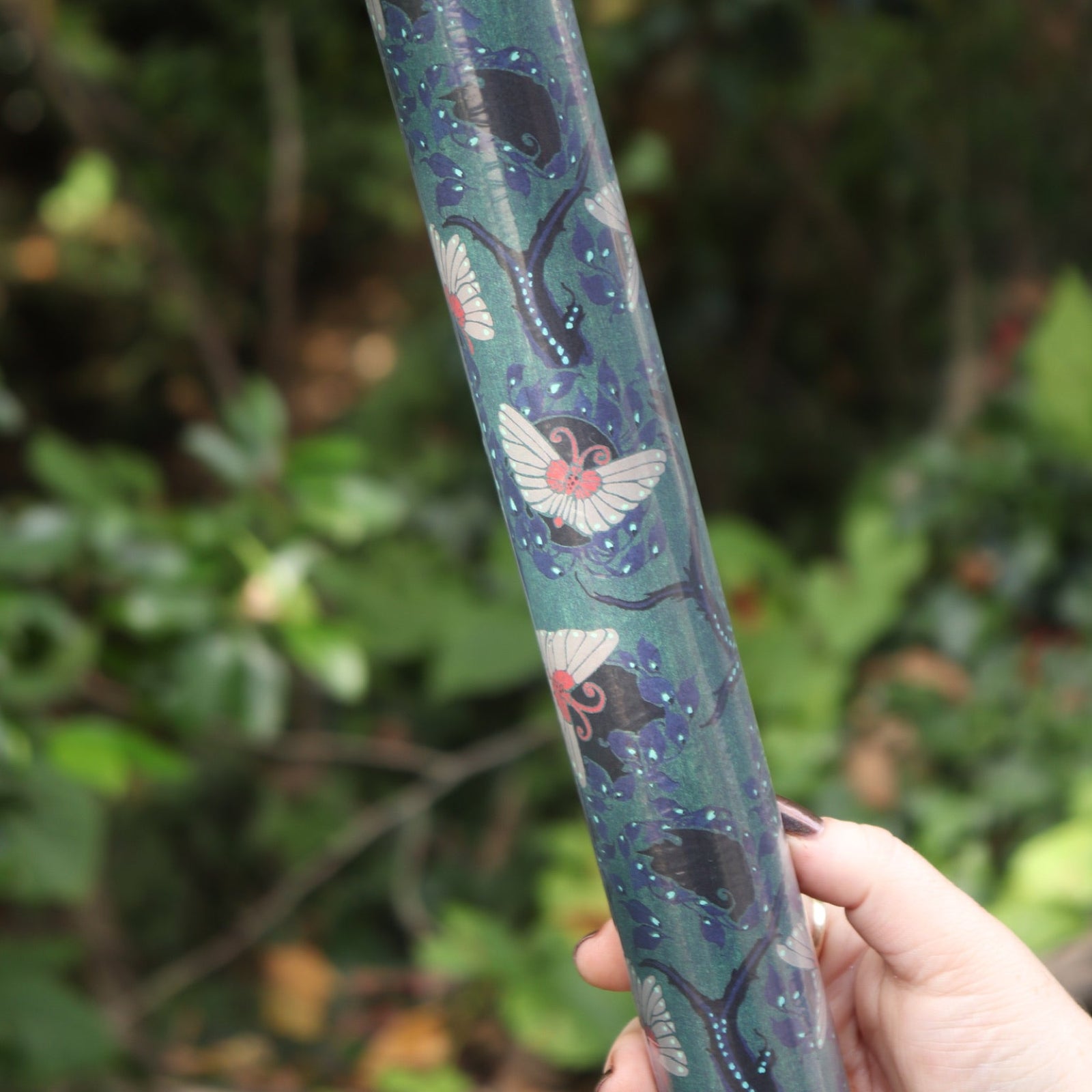 The Nouveau Twilight Butterflies Matte Fine Wrapping Paper in front of some greenery.