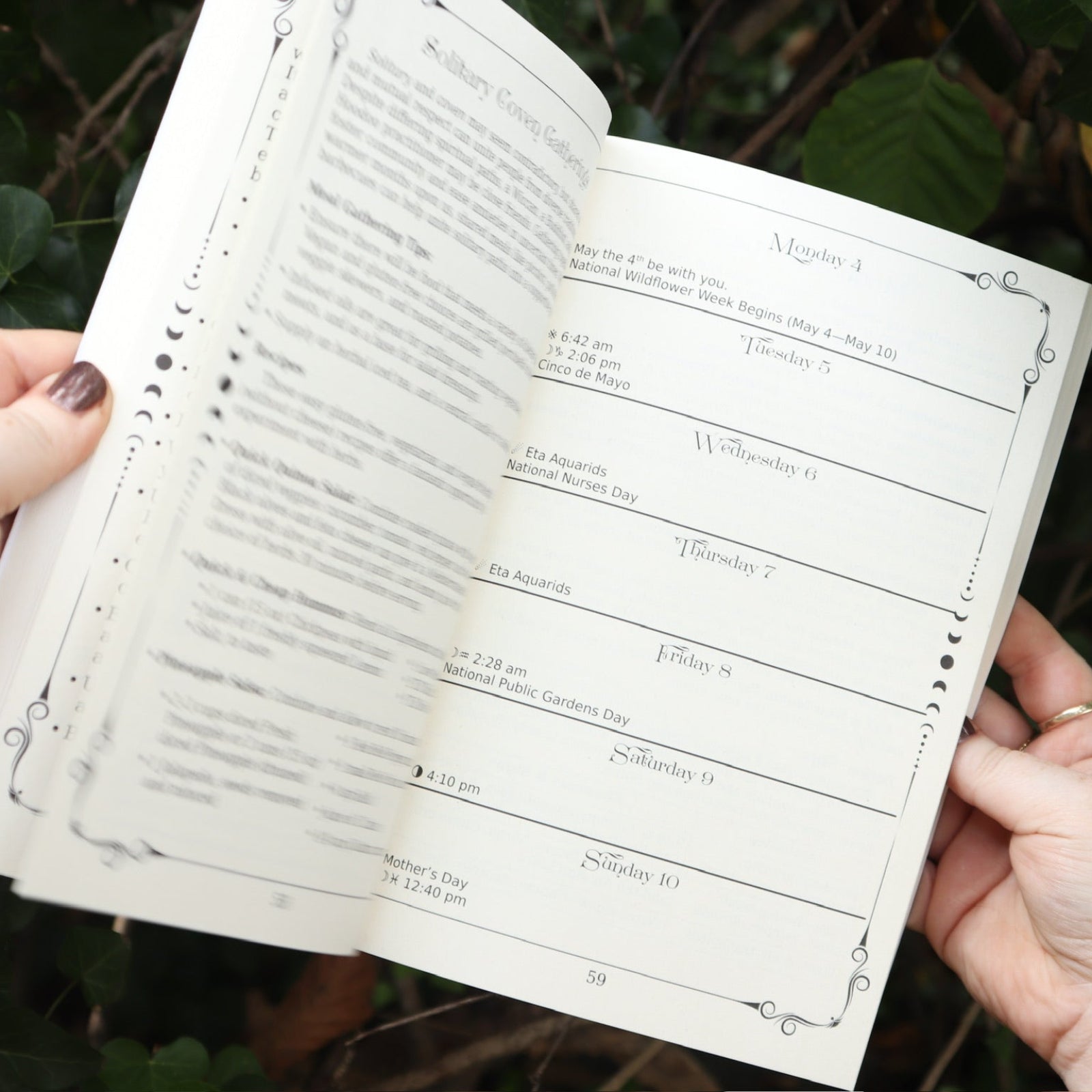 Someone holding The Practical Witch's 2026 Almanac open in front of some greenery.