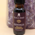 The Moon Goddess Reiki Charged Anointing Oil in front of an amethyst tower all on a pink and yellow background.