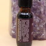 The Moon Goddess Reiki Charged Anointing Oil in front of an amethyst tower all on a pink and yellow background.