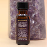The Sensual Lust & Passion Reiki Charged Anointing Oil in front of an amethyst tower all on a pink and yellow background.