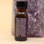 The Sensual Lust & Passion Reiki Charged Anointing Oil in front of an amethyst tower all on a pink and yellow background.