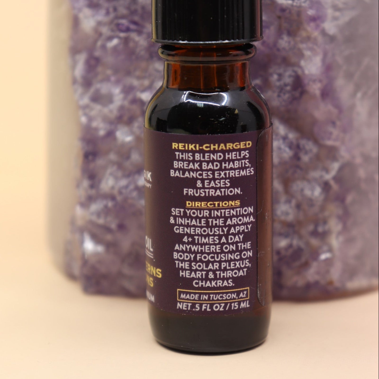 The Break Patterns & Addictions Oil Reiki Charged Anointing Oil in front of an amethyst tower all on a pink and yellow background.