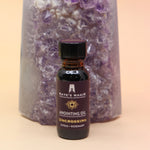 The Uncrossing Oil Reiki Charged Anointing Oil in front of an amethyst tower all on a pink and yellow background.