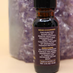 The Uncrossing Oil Reiki Charged Anointing Oil in front of an amethyst tower all on a pink and yellow background.