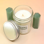 The Fog & Fern Soy Candle surrounded by green crystal tower all on a pink and yellow background.