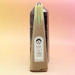 The straight Chartreuse Beeswax Taper Candles against a crystal tower all on a pink and yellow background.