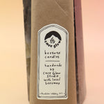 An up-close image of the packaging of the Cave Glow Studio Taper Candles against a crystal tower all on a pink and yellow background.