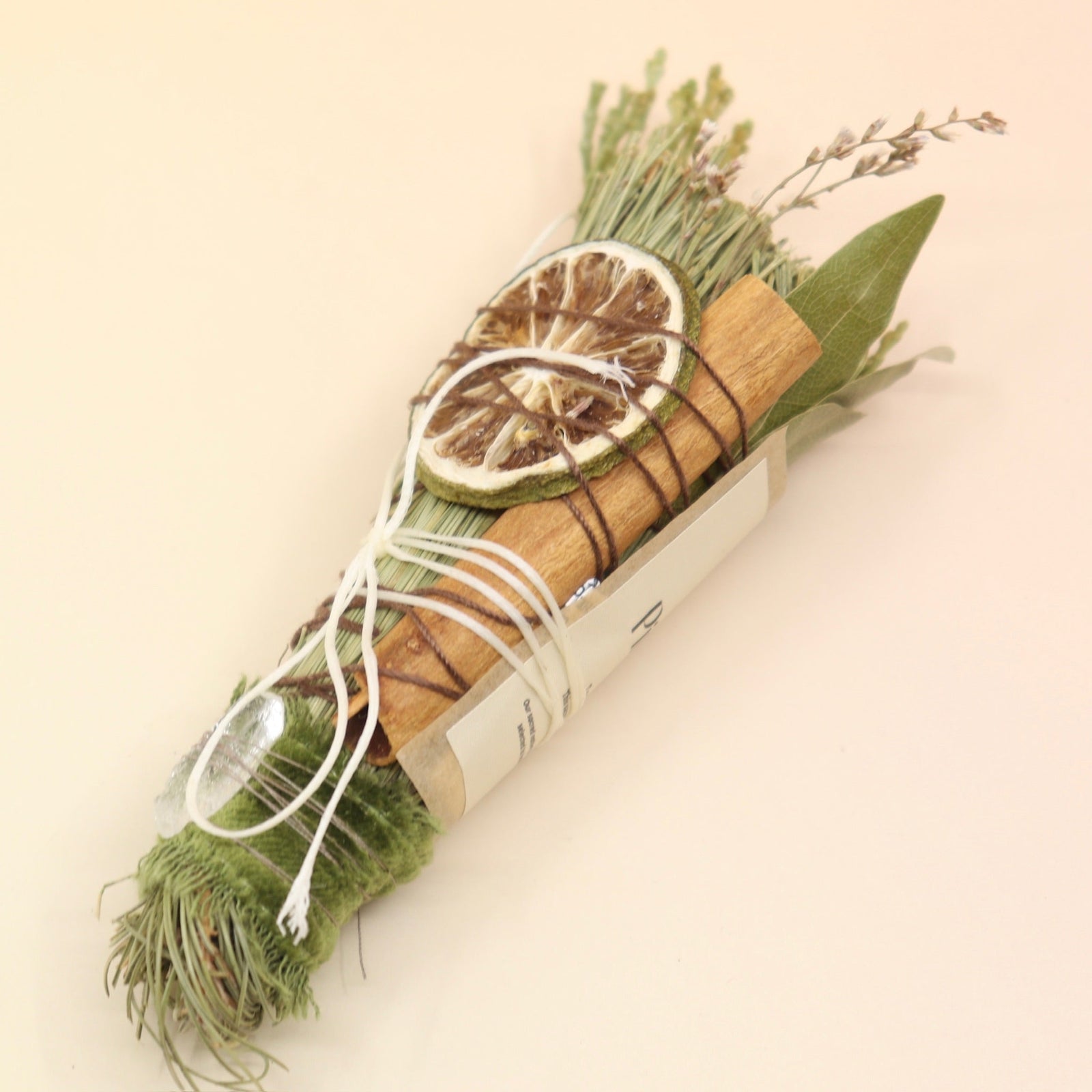 The Piñon Pine Sacred Smoke Cleansing Stick with Quartz Crystal on a pink and yellow background.