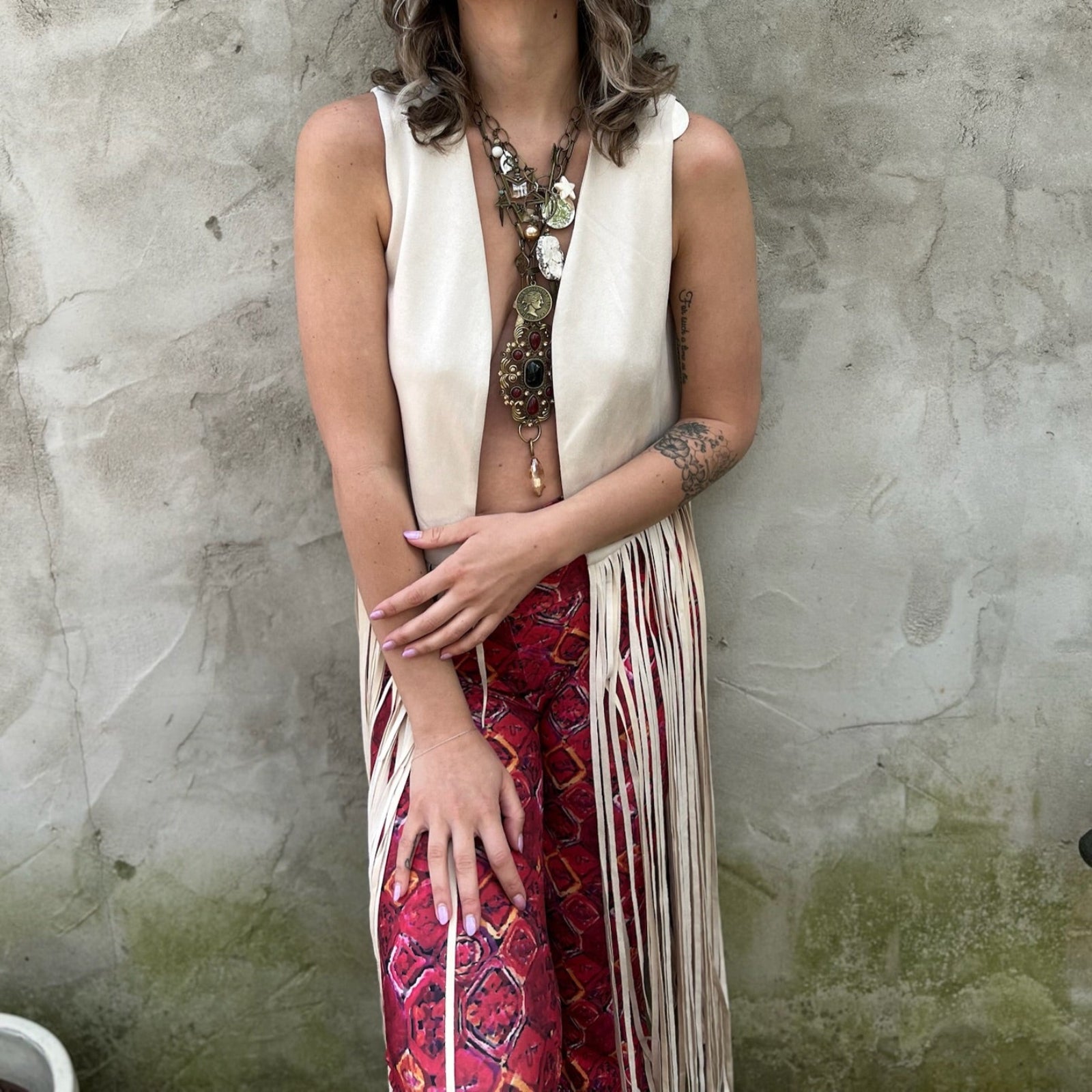 A woman wearing the cream Faux Suede Long Fringe Open Front Western Vest.