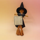 The pants Witch Samhain Folk Corn Husk Poppet Doll on a pink and yellow background. 