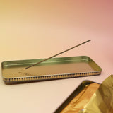 The Premium Incense on a pink and yellow background, showing off the inside of the tin.