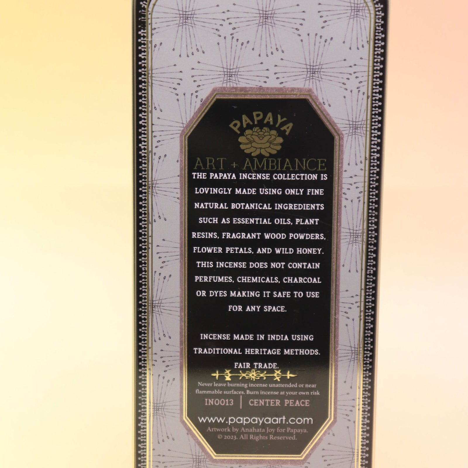 The Center Peace Premium Incense on a pink and yellow background, showing of the back.