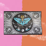 The Lunar Moth Cotton Tapestry in front of a pink and orange background.