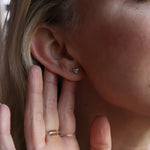 An up-close image of someone wearing the silver Memento Mori Mini Skull Stud Earrings.