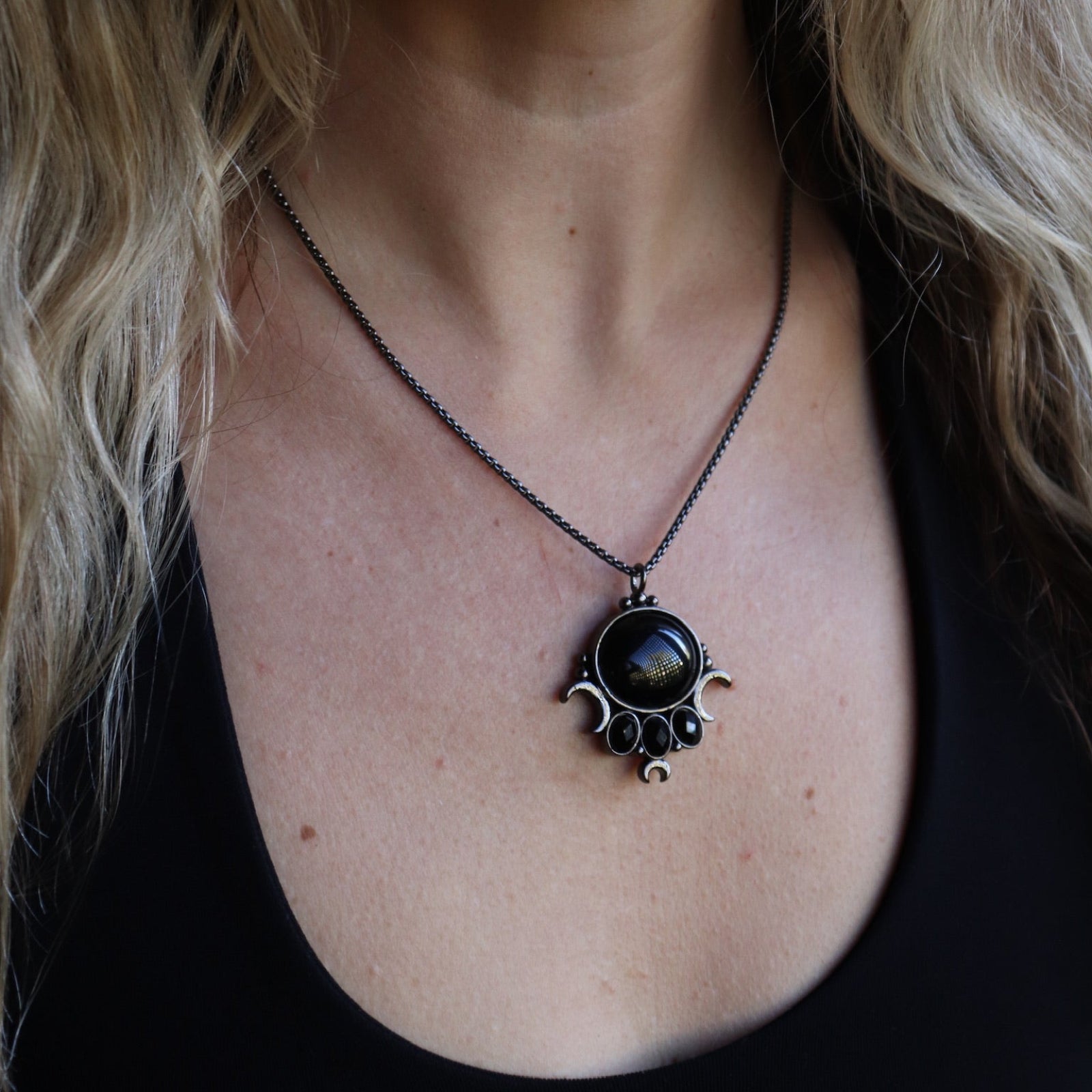 Someone wearing the Priestess Obsidian Brass Necklace.