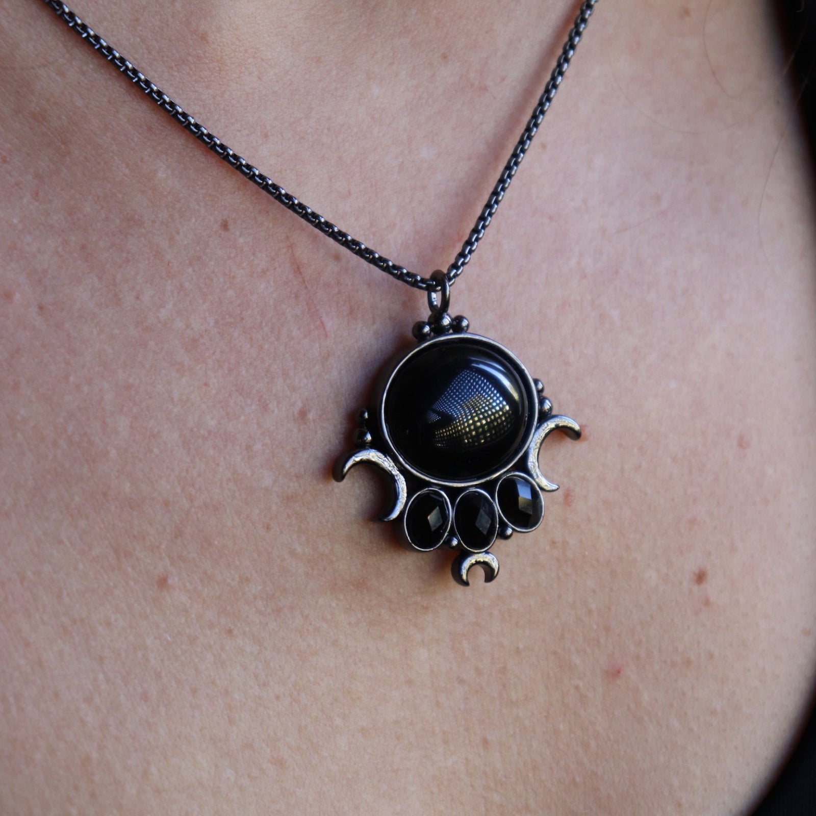 Someone wearing the Priestess Obsidian Brass Necklace.