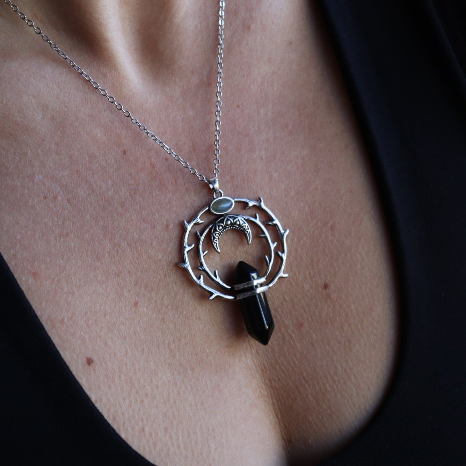 Someone wearing the Silver Thorn Crystal Necklace with a black tank.